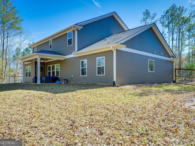 rear view of house featuring a lawn, fence, and a ceiling fan