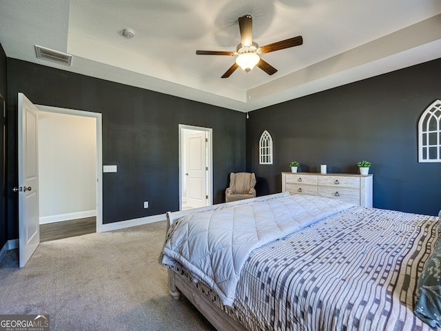 bedroom featuring baseboards, visible vents, a raised ceiling, a ceiling fan, and carpet floors