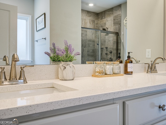 full bath featuring double vanity, a stall shower, and a sink