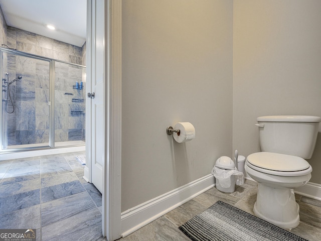 bathroom with a stall shower, toilet, and baseboards