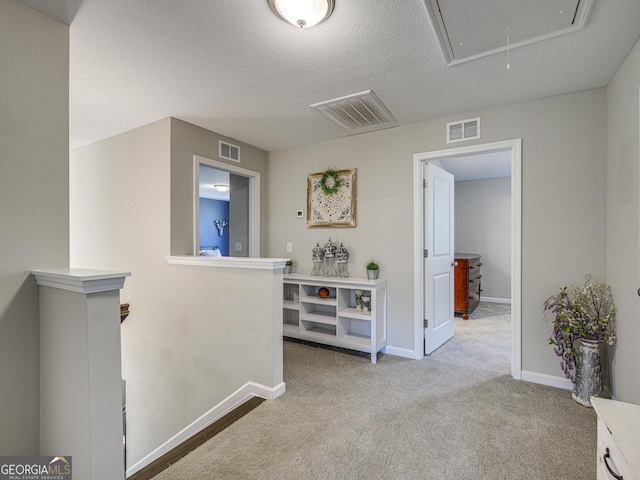 corridor featuring visible vents, an upstairs landing, and attic access