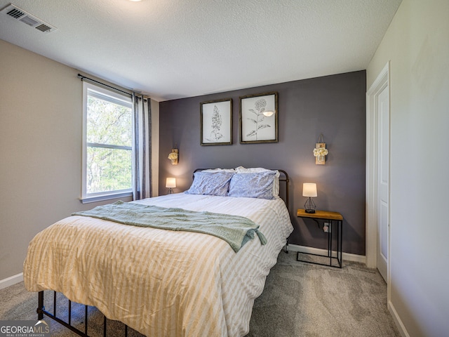 carpeted bedroom with a textured ceiling, visible vents, and baseboards