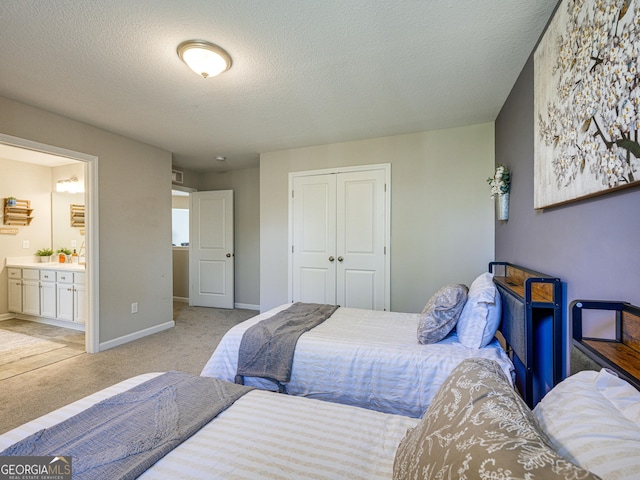 bedroom featuring a textured ceiling, connected bathroom, light carpet, baseboards, and a closet