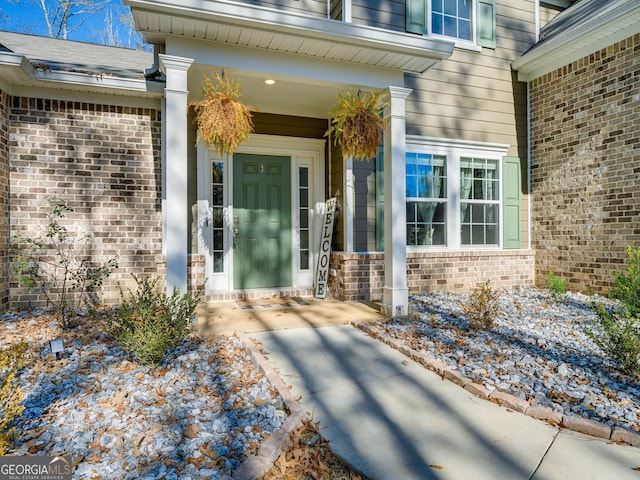 entrance to property with a porch and brick siding