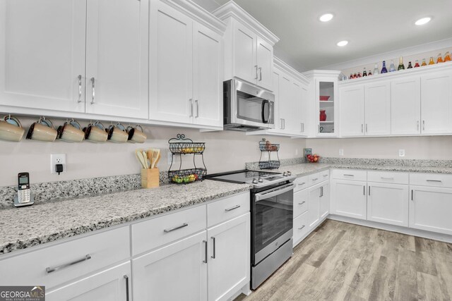 kitchen with appliances with stainless steel finishes, light stone counters, light hardwood / wood-style floors, and white cabinets