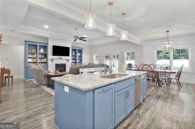 kitchen featuring decorative light fixtures, sink, a kitchen island with sink, ceiling fan with notable chandelier, and wood-type flooring