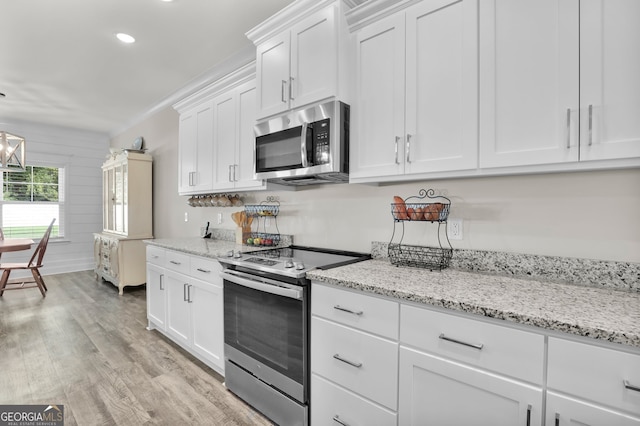 kitchen featuring white cabinets, light hardwood / wood-style flooring, light stone counters, and stainless steel appliances