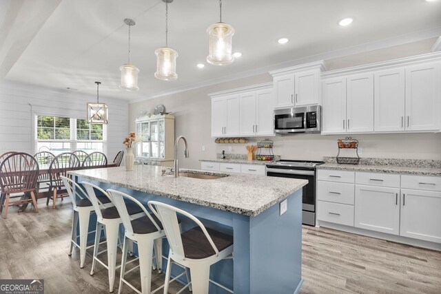 kitchen with stainless steel appliances, decorative light fixtures, sink, light wood-type flooring, and white cabinets