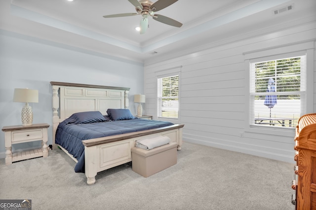 carpeted bedroom featuring ceiling fan, a tray ceiling, and multiple windows