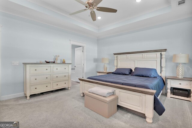 carpeted bedroom featuring ceiling fan, a raised ceiling, and ensuite bath