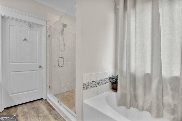 bathroom featuring hardwood / wood-style flooring and shower with separate bathtub