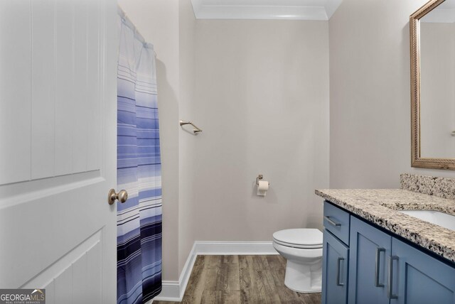 bathroom with hardwood / wood-style flooring, toilet, vanity, and ornamental molding