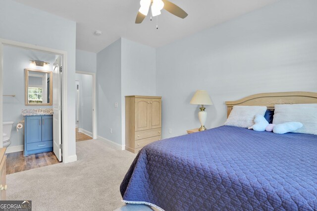 bedroom with light hardwood / wood-style flooring, ceiling fan, and ensuite bath