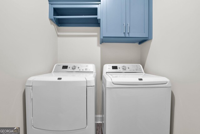 clothes washing area featuring washing machine and dryer and cabinets