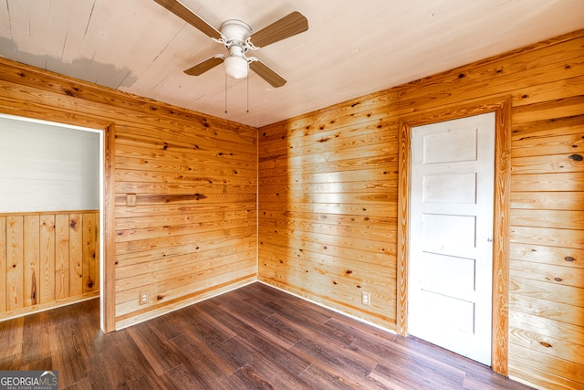 spare room featuring hardwood / wood-style flooring, wooden walls, and ceiling fan