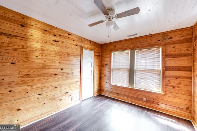 spare room with ceiling fan, wood walls, and wood-type flooring