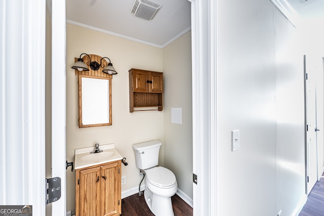 bathroom with hardwood / wood-style flooring, crown molding, vanity, and toilet