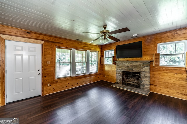 unfurnished living room with wood walls, a wealth of natural light, and dark hardwood / wood-style flooring