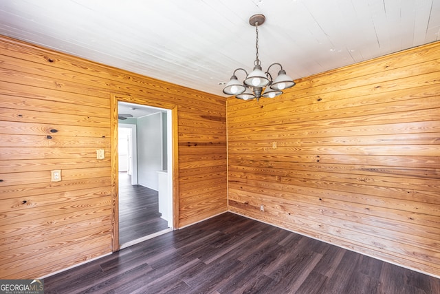 unfurnished room with a notable chandelier, wooden walls, and hardwood / wood-style floors