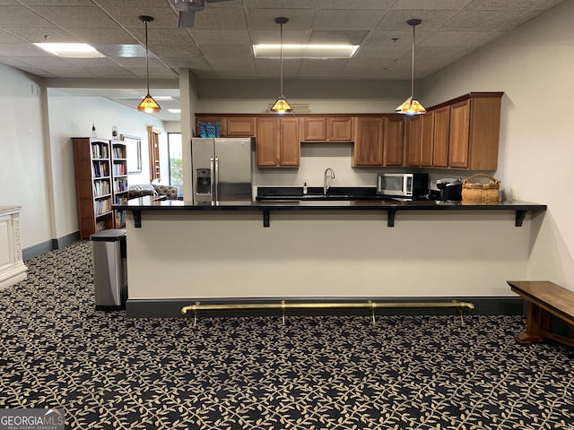 kitchen with a breakfast bar, pendant lighting, stainless steel appliances, dark countertops, and a peninsula