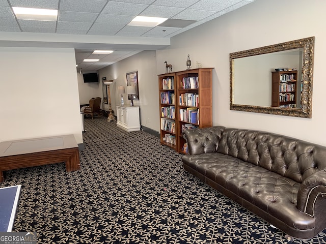 carpeted living area featuring baseboards and a drop ceiling