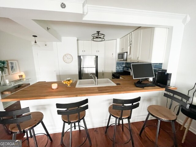 kitchen featuring a breakfast bar, sink, appliances with stainless steel finishes, dark hardwood / wood-style floors, and white cabinetry