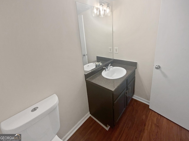 half bath with wood finished floors, vanity, and baseboards