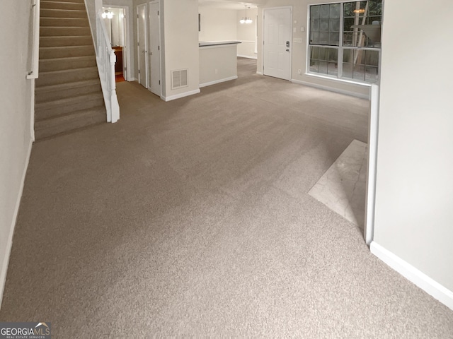 unfurnished living room featuring stairway, carpet flooring, visible vents, and baseboards