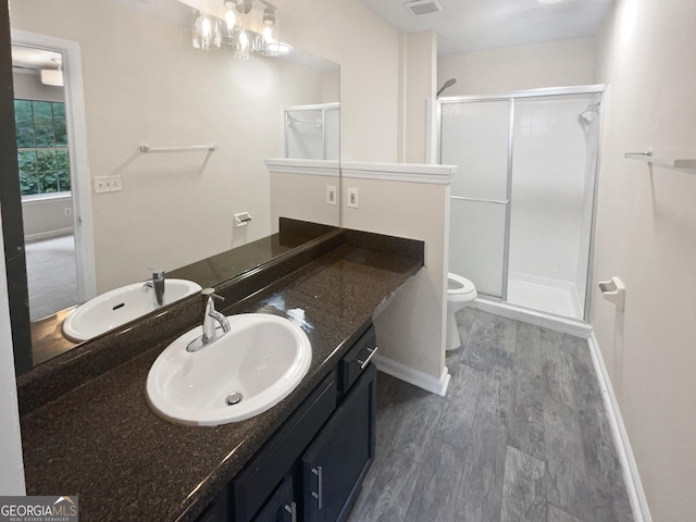 full bathroom featuring toilet, wood finished floors, a shower stall, and vanity