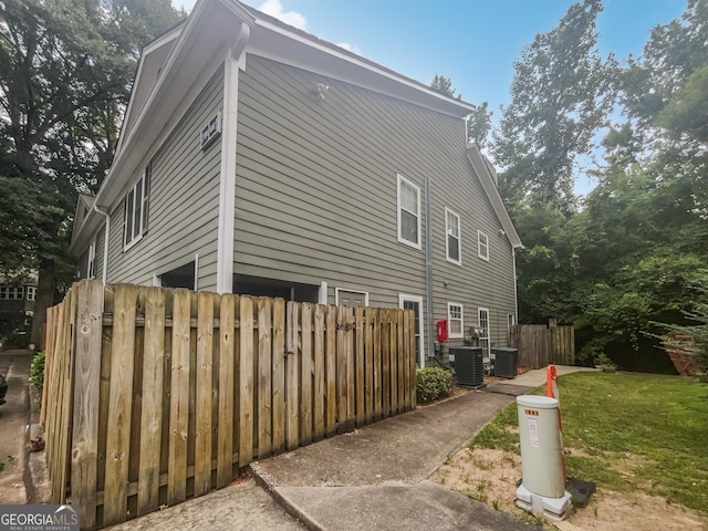 view of side of property featuring central air condition unit, fence, and a yard