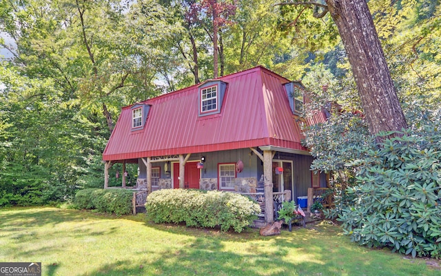 view of front of house featuring stone siding, a front yard, covered porch, and metal roof