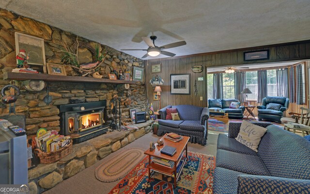 living area with a stone fireplace, wood walls, a textured ceiling, and ceiling fan