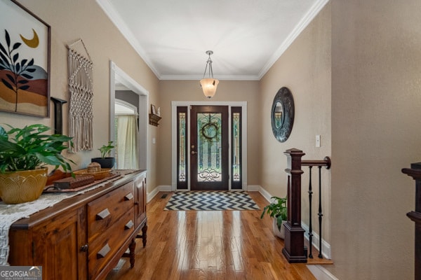 foyer entrance with light wood-type flooring and ornamental molding