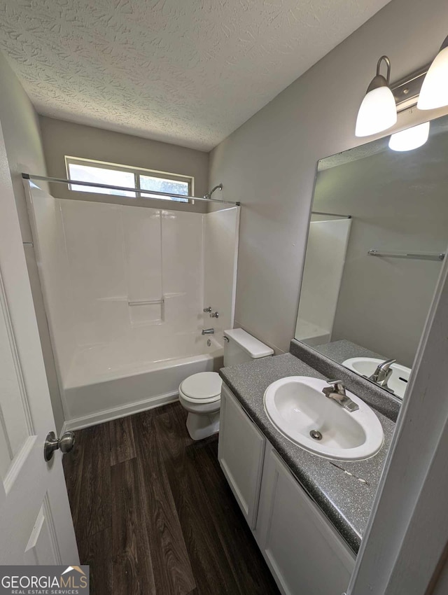 full bathroom with toilet, vanity, hardwood / wood-style floors, tub / shower combination, and a textured ceiling