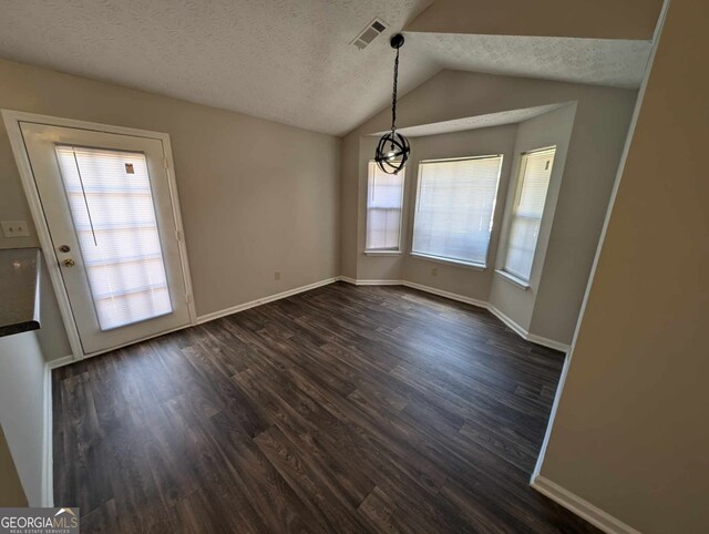 unfurnished dining area with a wealth of natural light, dark wood-type flooring, a textured ceiling, and lofted ceiling