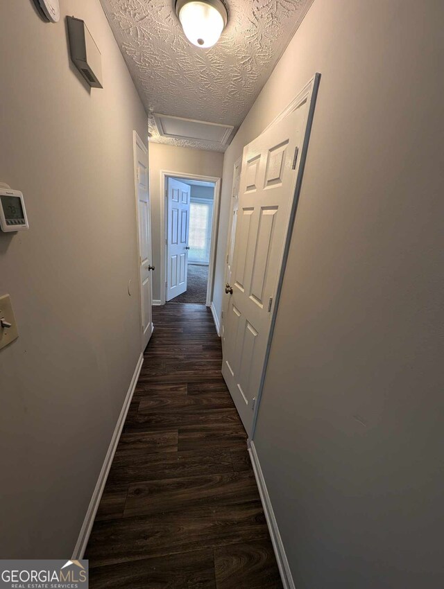 corridor with dark hardwood / wood-style flooring and a textured ceiling