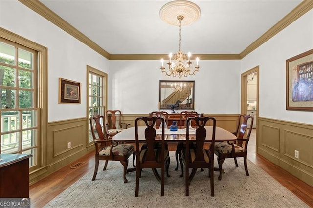 dining area with ornamental molding, light hardwood / wood-style flooring, and a notable chandelier