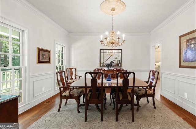 dining space featuring wood-type flooring, a chandelier, and crown molding