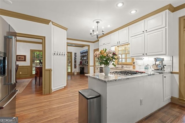 kitchen featuring pendant lighting, light stone counters, white cabinetry, and light hardwood / wood-style floors