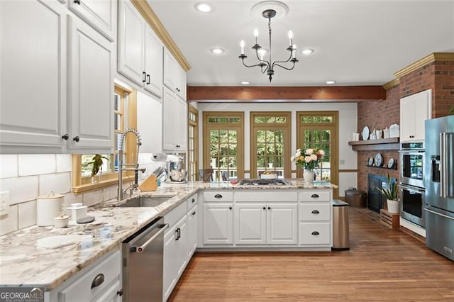 kitchen featuring pendant lighting, sink, appliances with stainless steel finishes, and light hardwood / wood-style floors