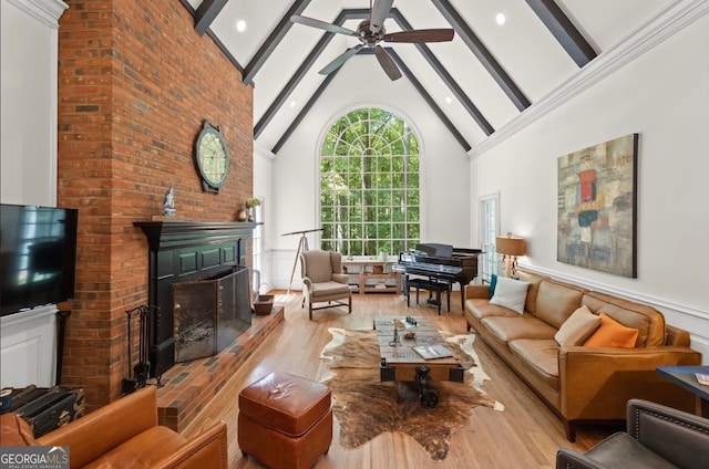 living room featuring high vaulted ceiling, ceiling fan, beamed ceiling, and a brick fireplace