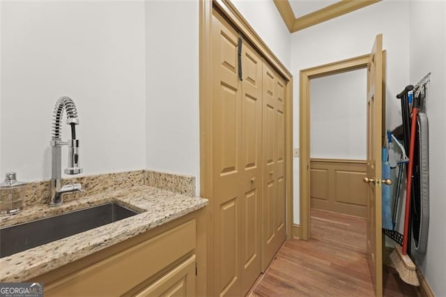 interior space with light wood-type flooring, ornamental molding, and sink