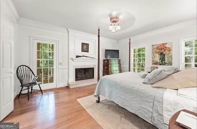 bedroom with light wood-type flooring, multiple windows, and ornamental molding