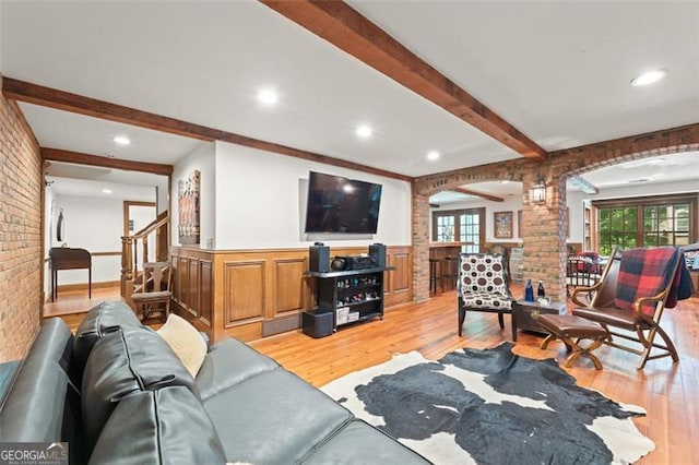 living room featuring brick wall, plenty of natural light, and light hardwood / wood-style flooring