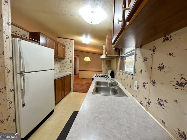 kitchen featuring sink, white refrigerator, a textured ceiling, light tile patterned floors, and hanging light fixtures