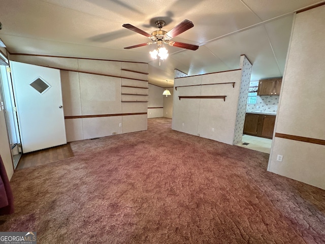 unfurnished living room featuring ceiling fan, vaulted ceiling, and carpet