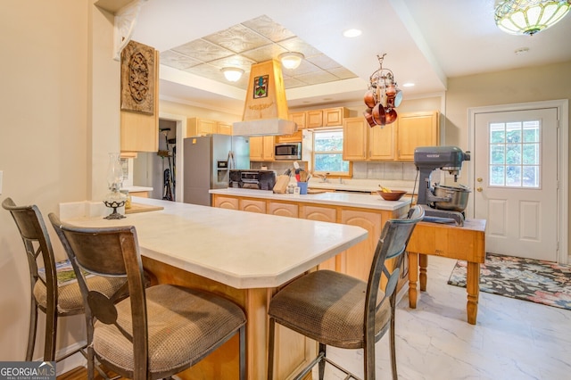 kitchen featuring decorative backsplash, light brown cabinetry, a raised ceiling, stainless steel appliances, and kitchen peninsula