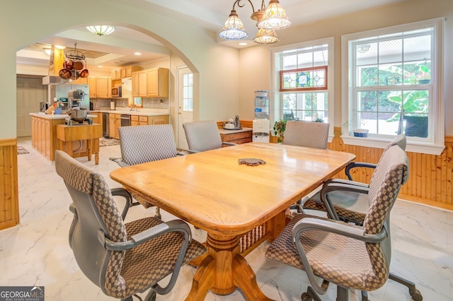 tiled dining room with a raised ceiling and a chandelier