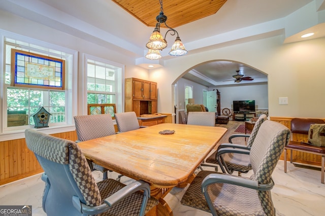 dining space featuring a tray ceiling, ornamental molding, ceiling fan with notable chandelier, and light tile patterned floors