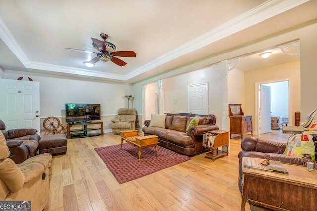 living room featuring ceiling fan, light wood-type flooring, a raised ceiling, and crown molding